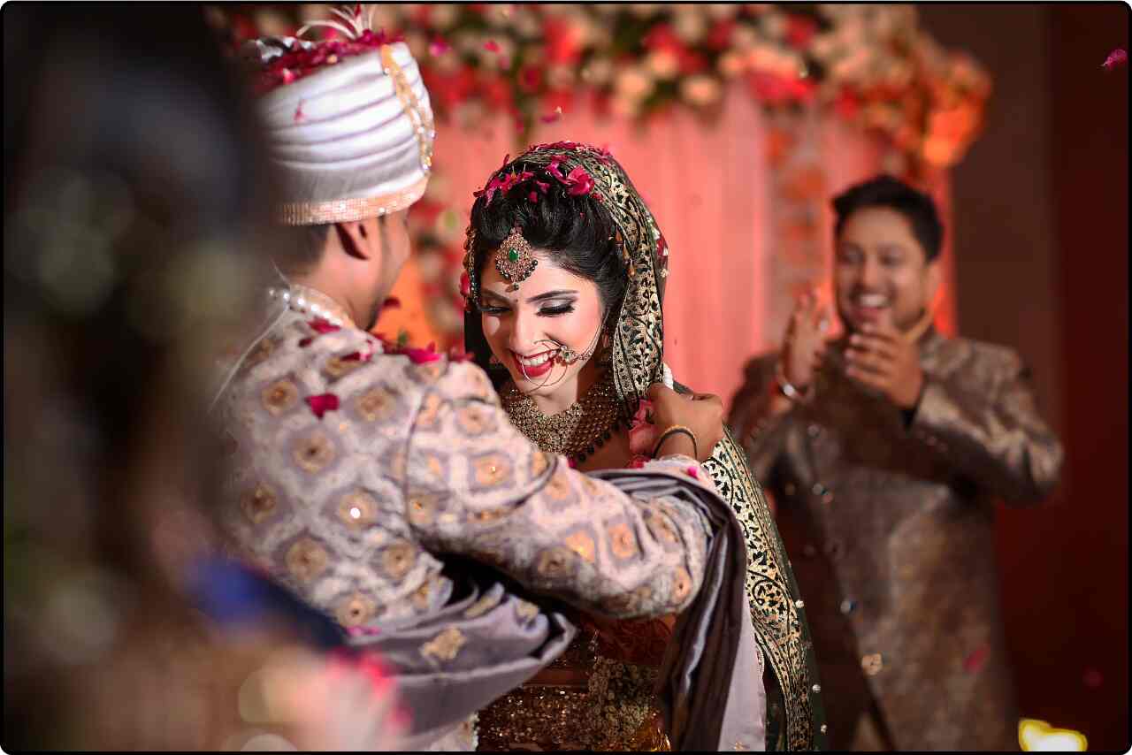 Indian bride and groom holding hands and exchanging Garland during their traditional wedding ceremony.